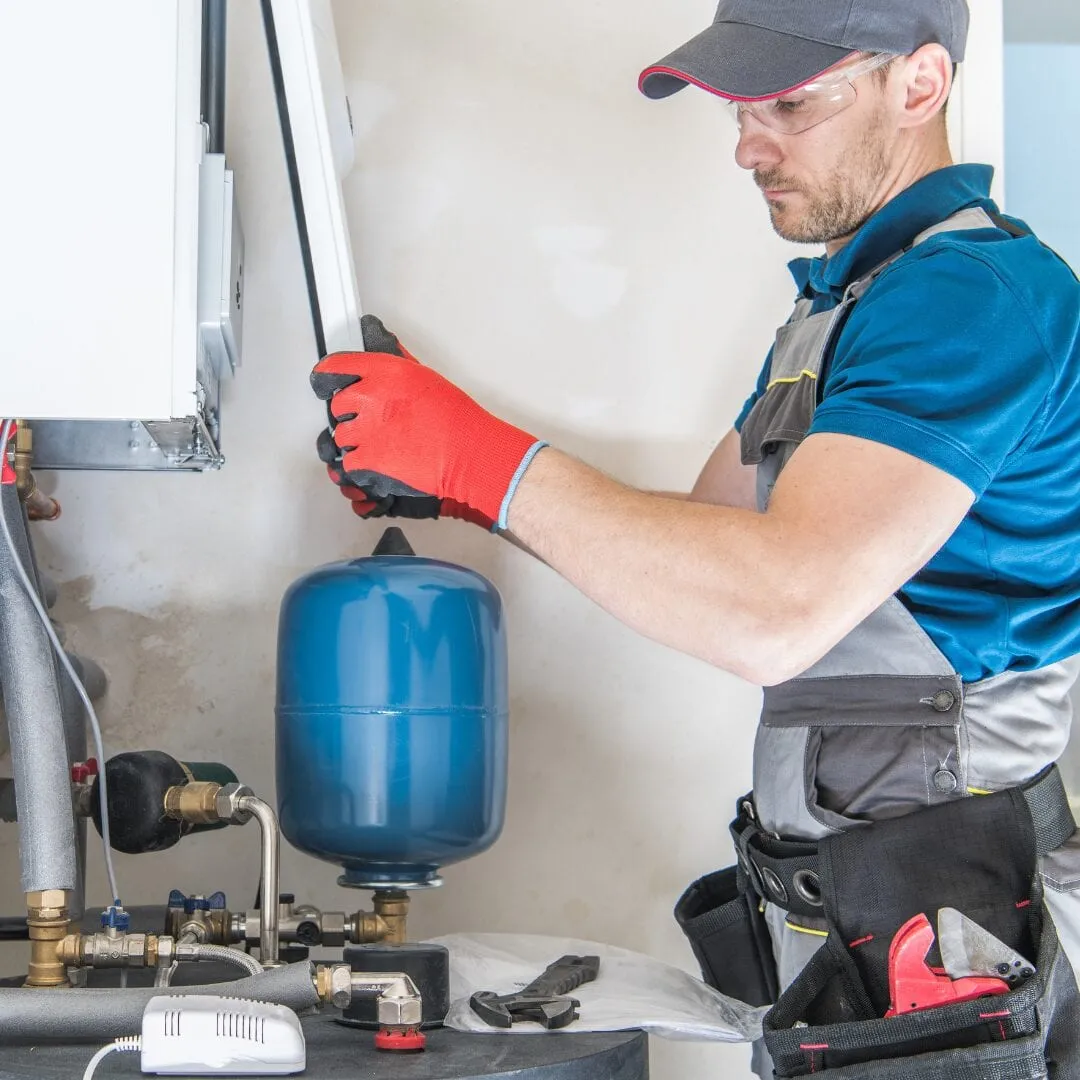 Plumber installing a water heater and pressure tank
