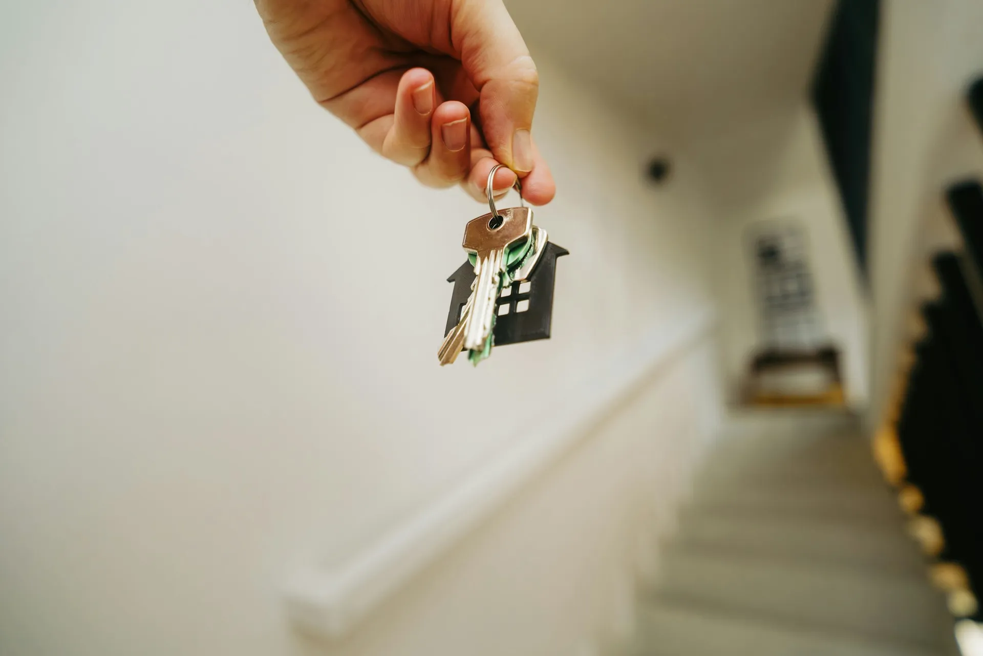 Hand holding a set of house keys inside a bright new home
