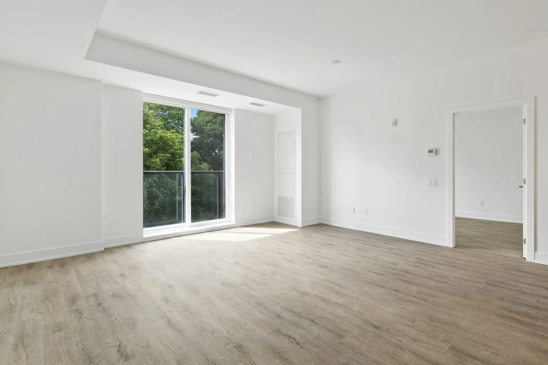 Bright empty new apartment with light wood flooring and a balcony door, ready for renovation
