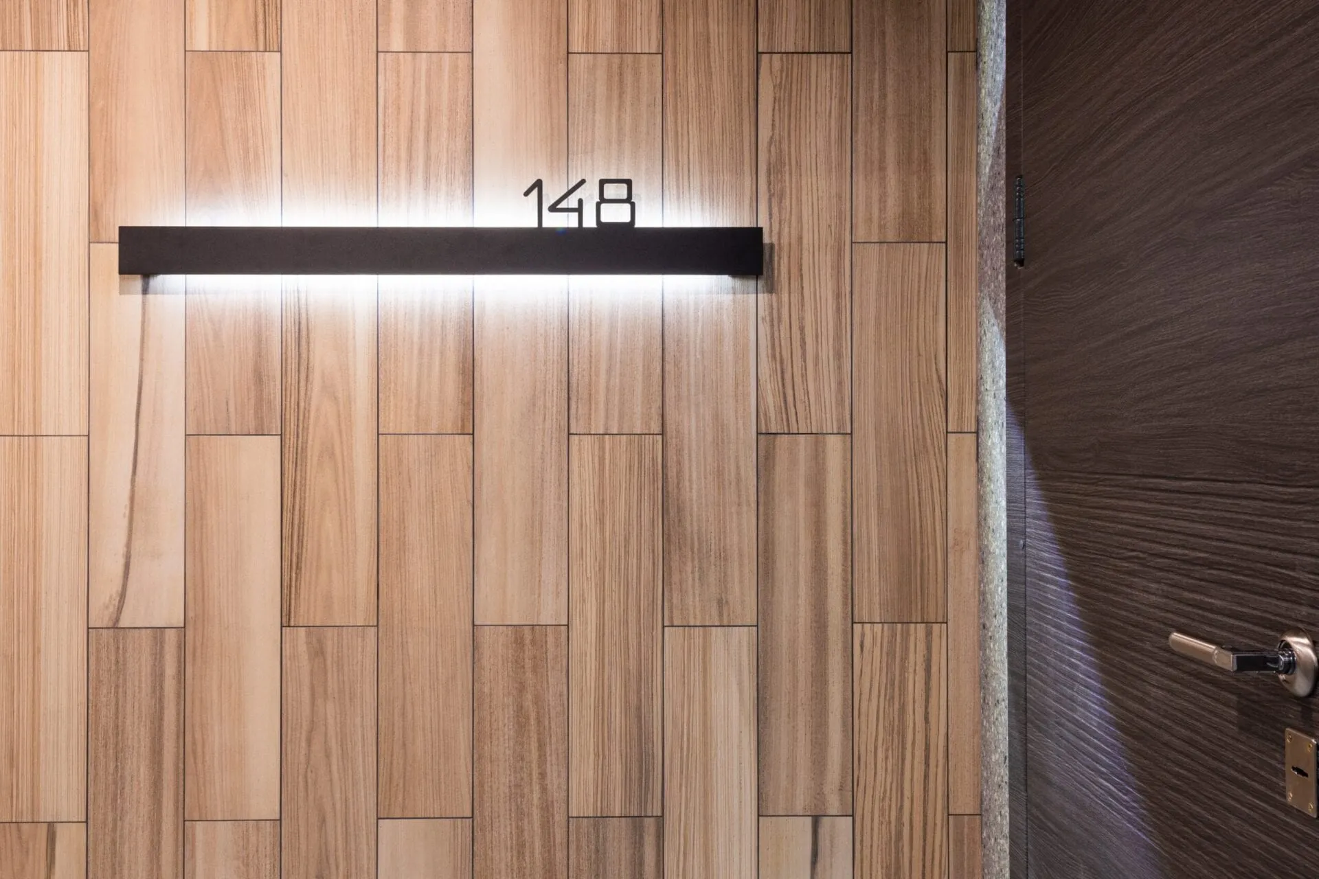 Timber front door of a new home with a lit unit number