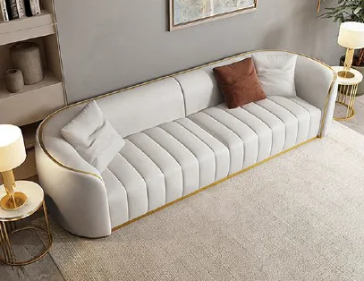 Cream channel-tufted curved sofa with gold trim in a living room
