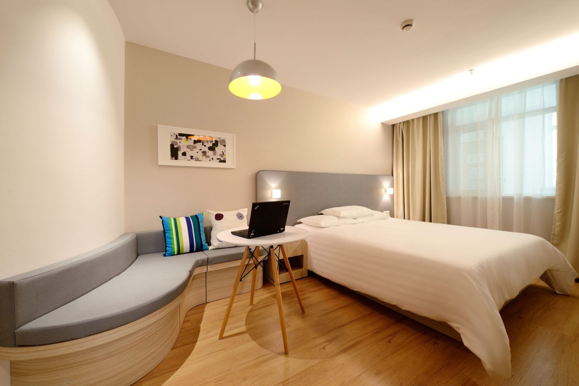 Hotel-style bedroom with a curved built-in bench seat, oak flooring and a pendant light