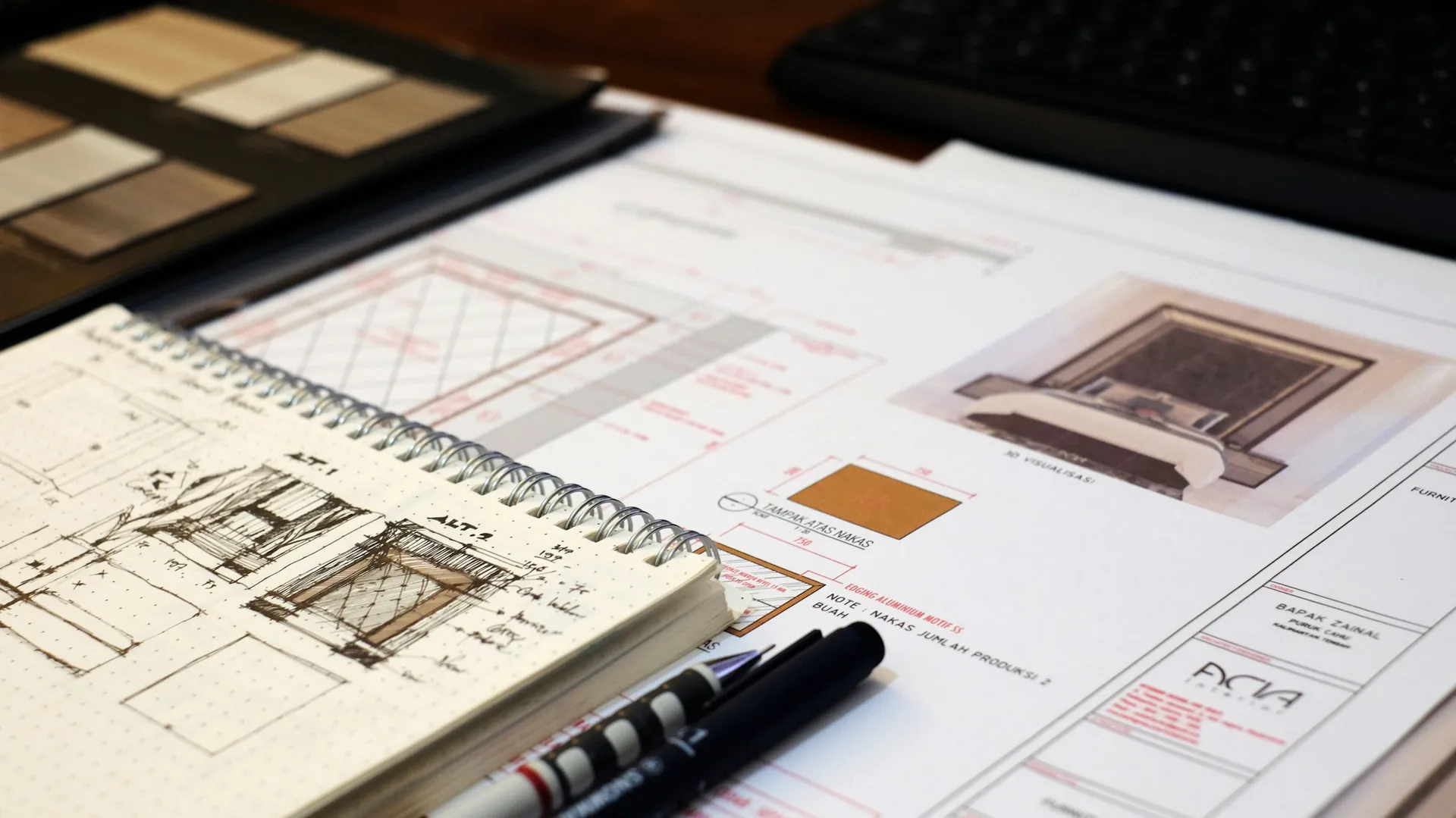 Interior design sketches, floor plans and material samples spread across a desk