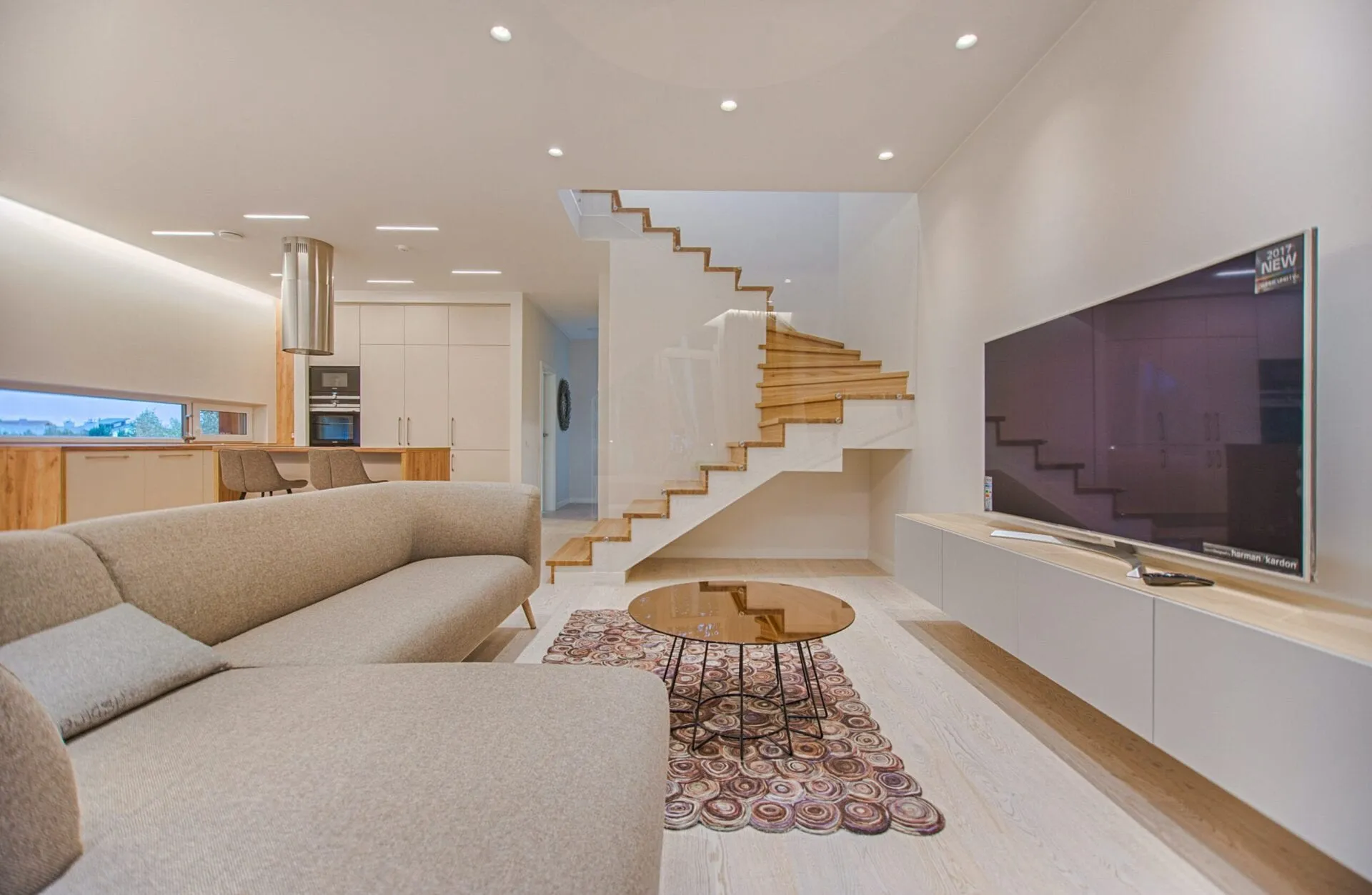 Bright modern living room with a floating staircase, cream sofa and wall-mounted TV