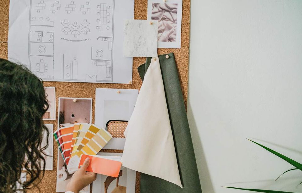 Designer pinning colour swatches and fabric samples to a mood board beside a floor plan