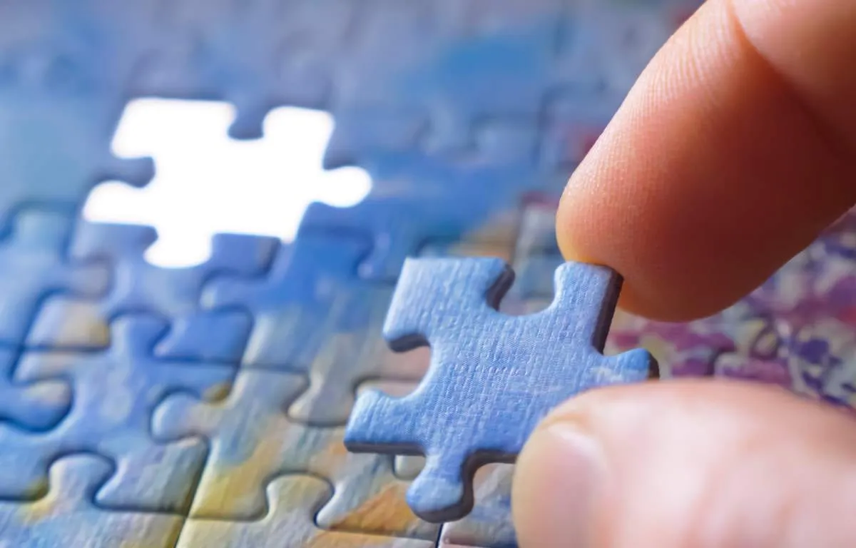 Hand placing the final piece of a jigsaw puzzle
