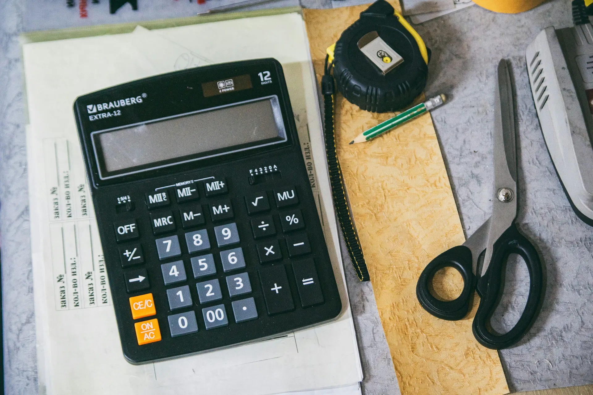 Calculator, measuring tape and paperwork on a desk for planning renovation payments