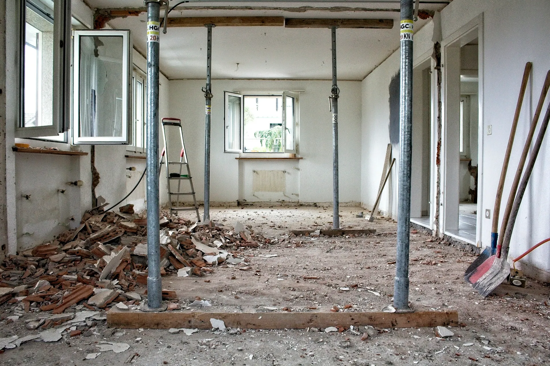 Apartment under renovation with exposed floor, debris and temporary support poles