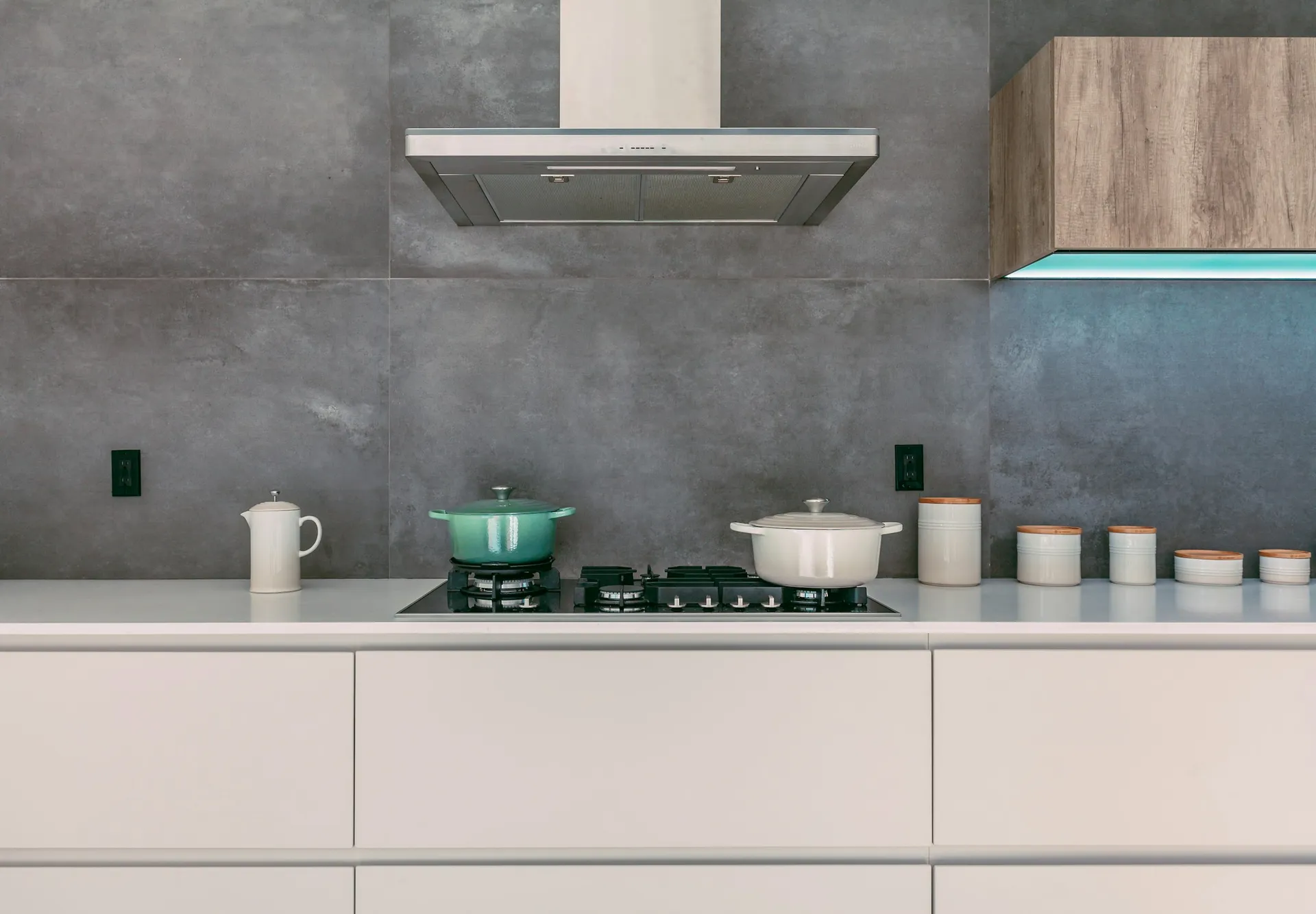 Built-in induction hob on a stone countertop with a stainless steel chimney hood above