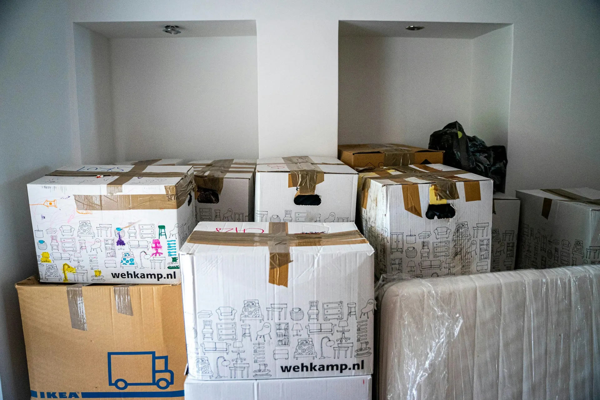 Sealed cardboard boxes stacked in an empty room, waiting to be unpacked