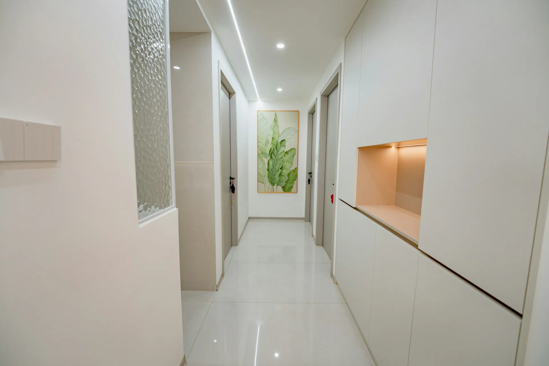 Entrance corridor with full-height white cabinets and a lit display niche