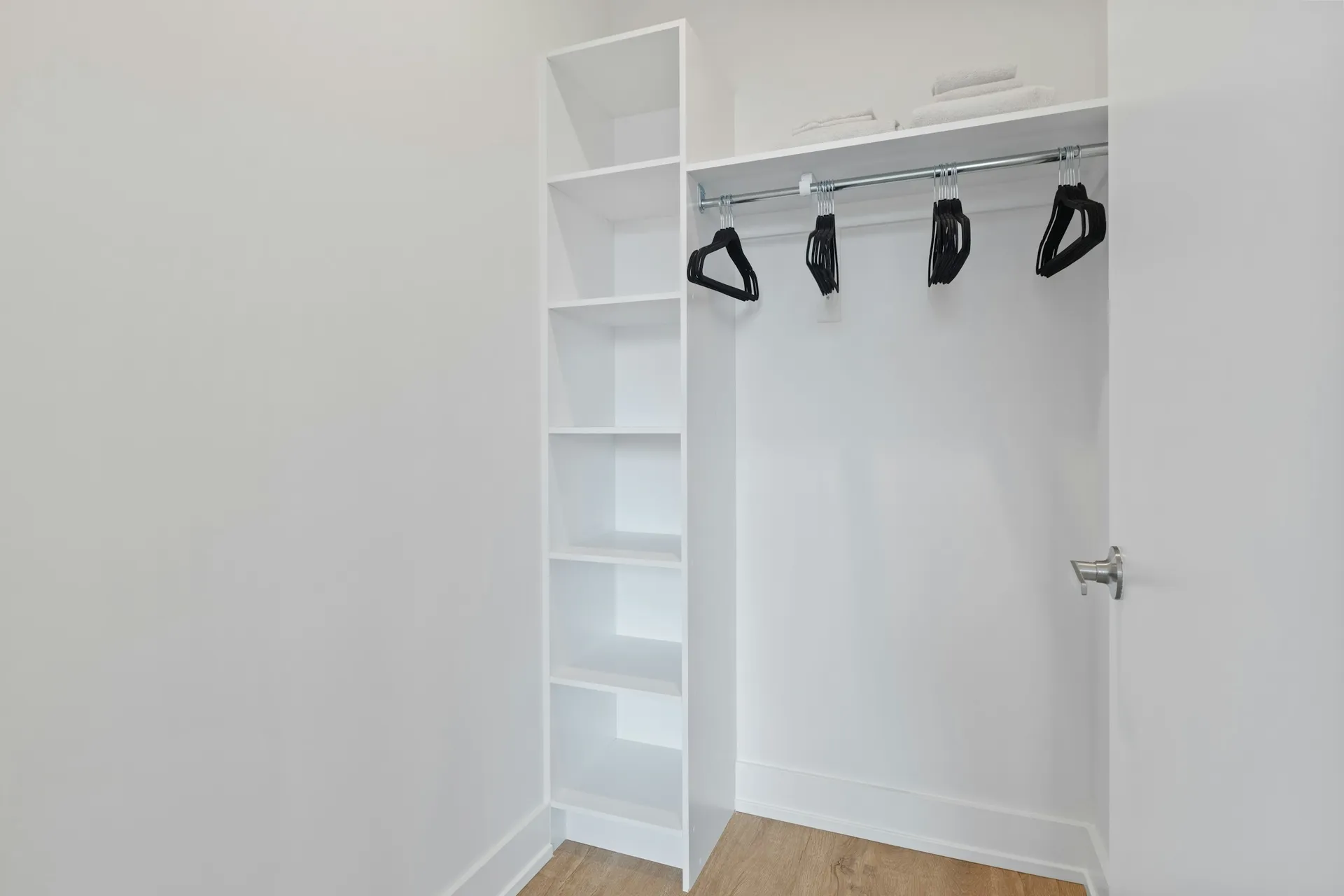 Empty white closet with a tall shelf column and a hanging rail