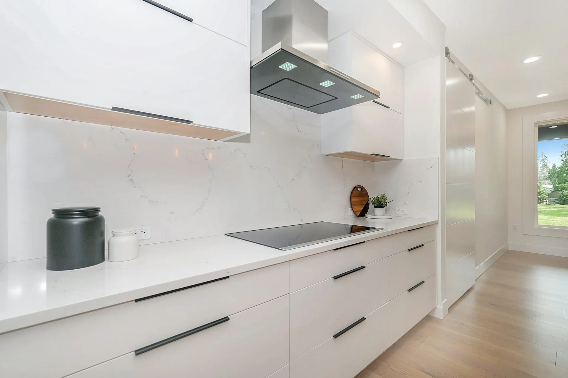 White handleless kitchen cabinets with a slim cooker hood and long counter
