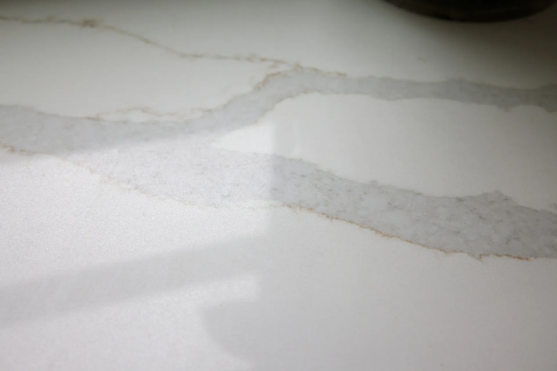 Close view of a pale stone kitchen countertop with a sink, tap and chopping board