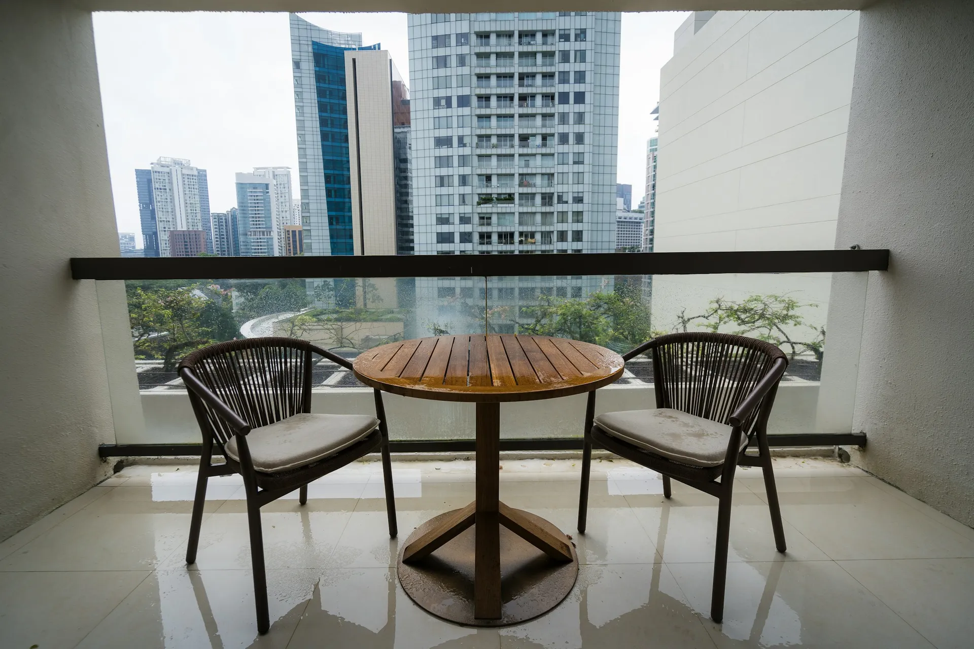 Round bistro table with two chairs on a balcony facing city towers