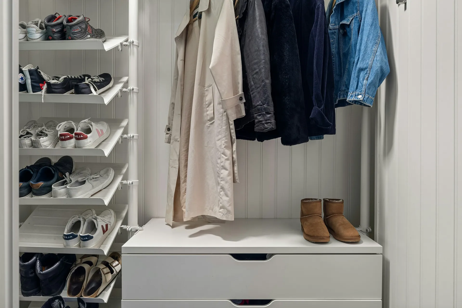Angled shoe shelves beside a hanging rail and drawer unit in a wardrobe