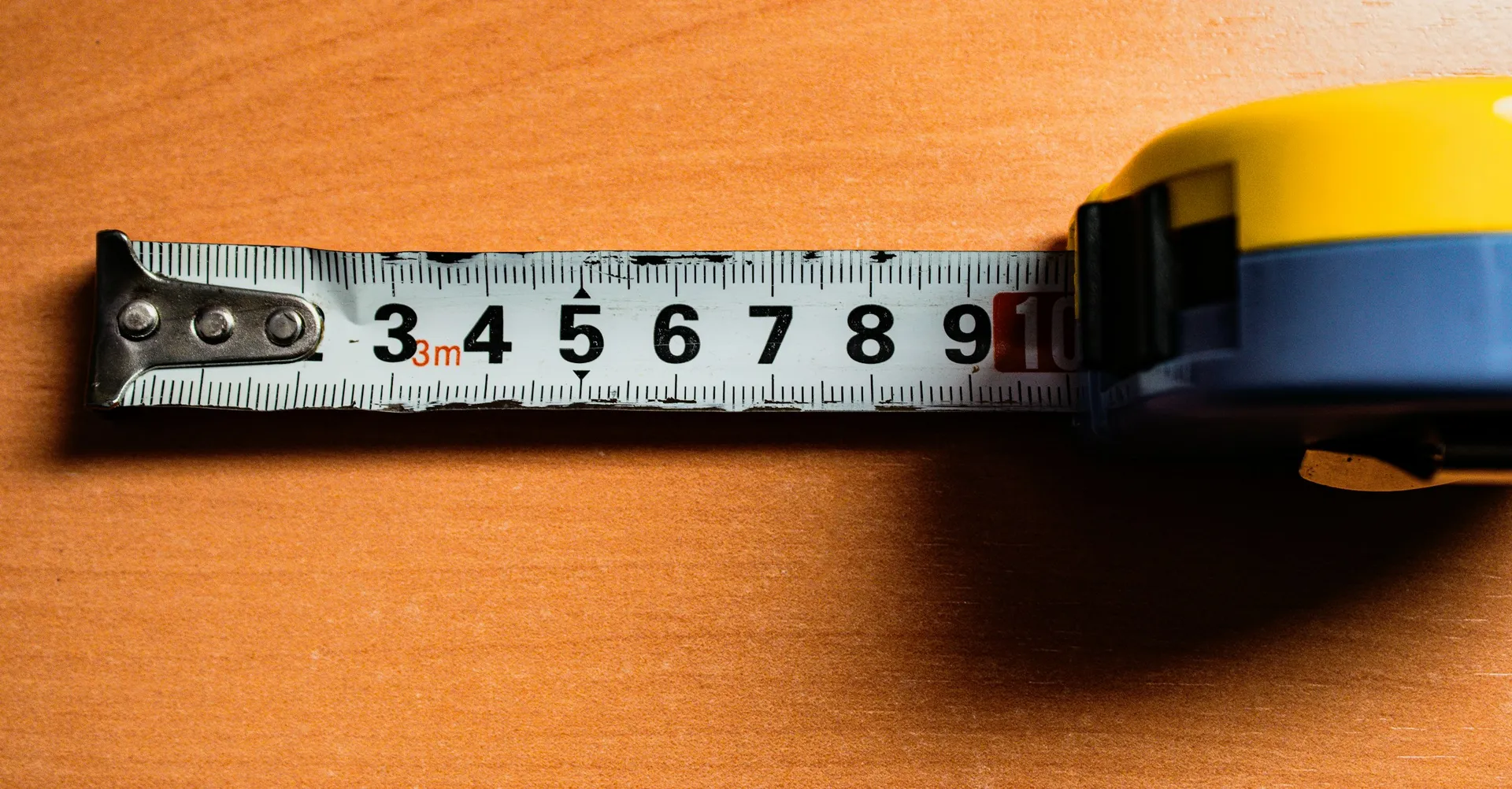 A yellow measuring tape lying open on a wooden table