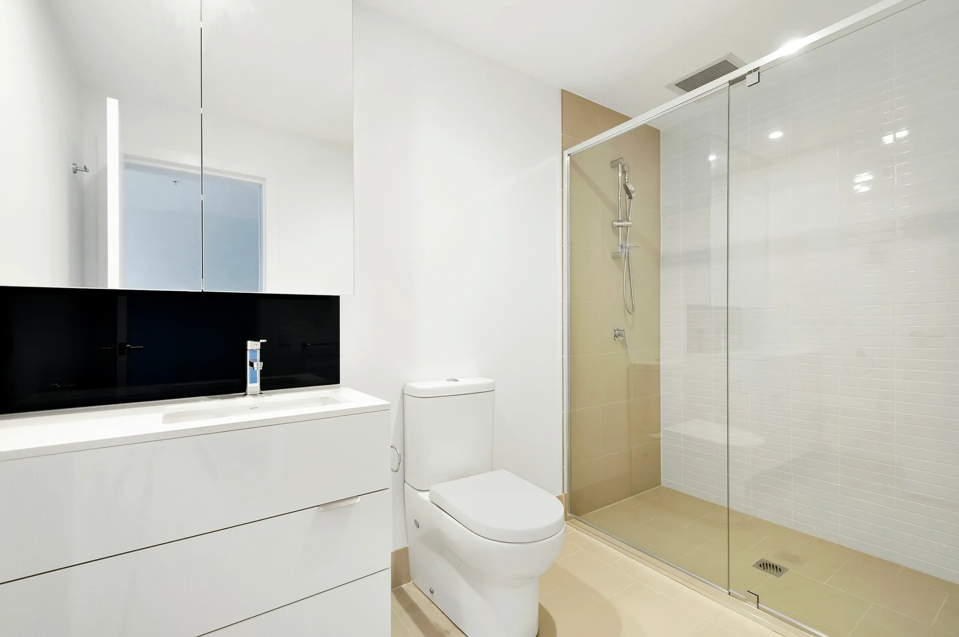 Walk-in shower behind a frameless glass screen next to a wall-hung toilet