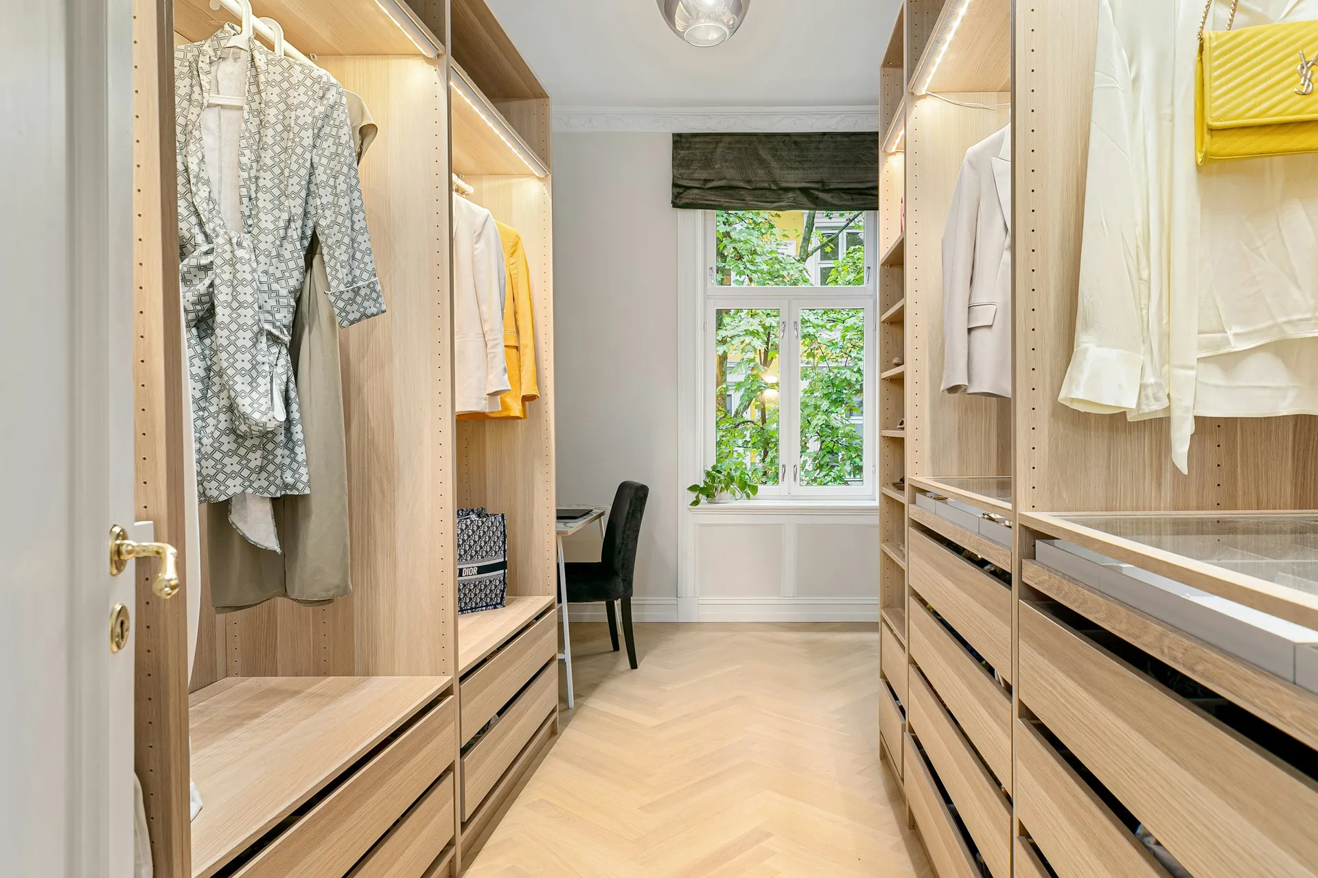 Walk-in wardrobe with light wood drawers and open hanging on both sides