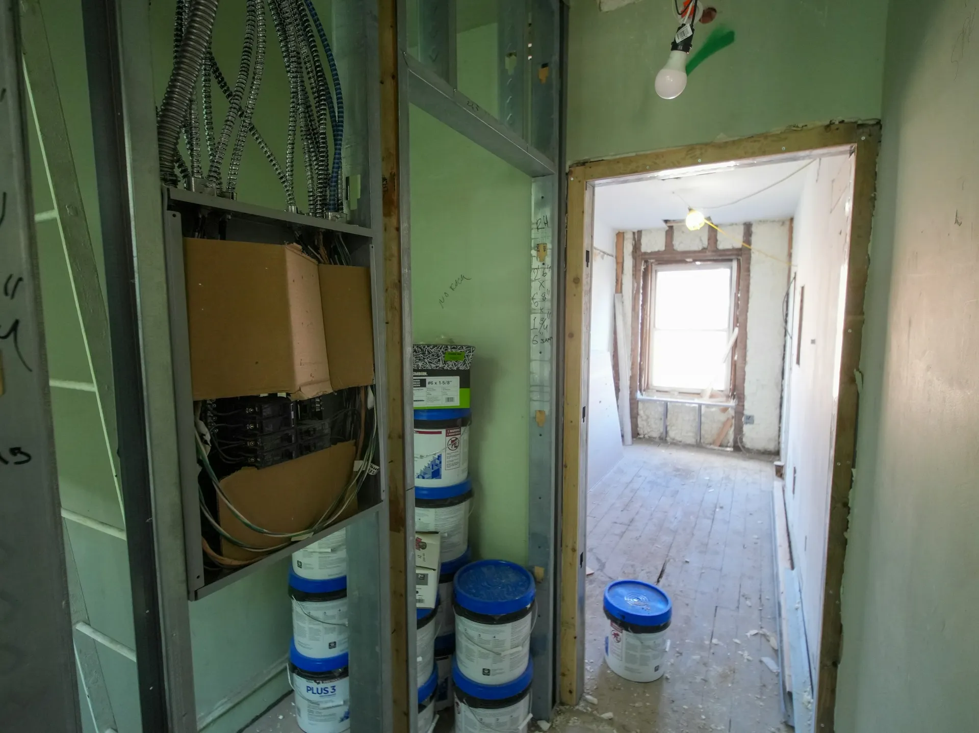 A flat in the middle of renovation, with paint tins and exposed wiring in the corridor