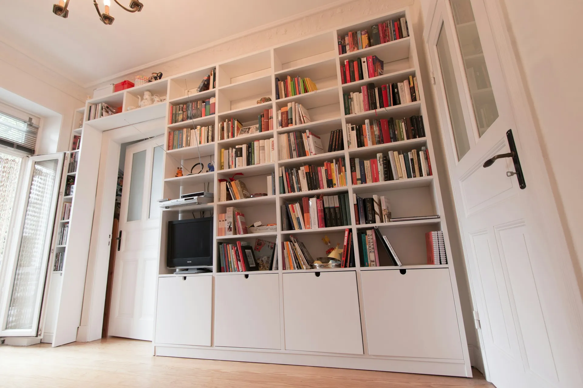 Full-height white built-in bookshelves with a recessed TV niche and lower cabinets