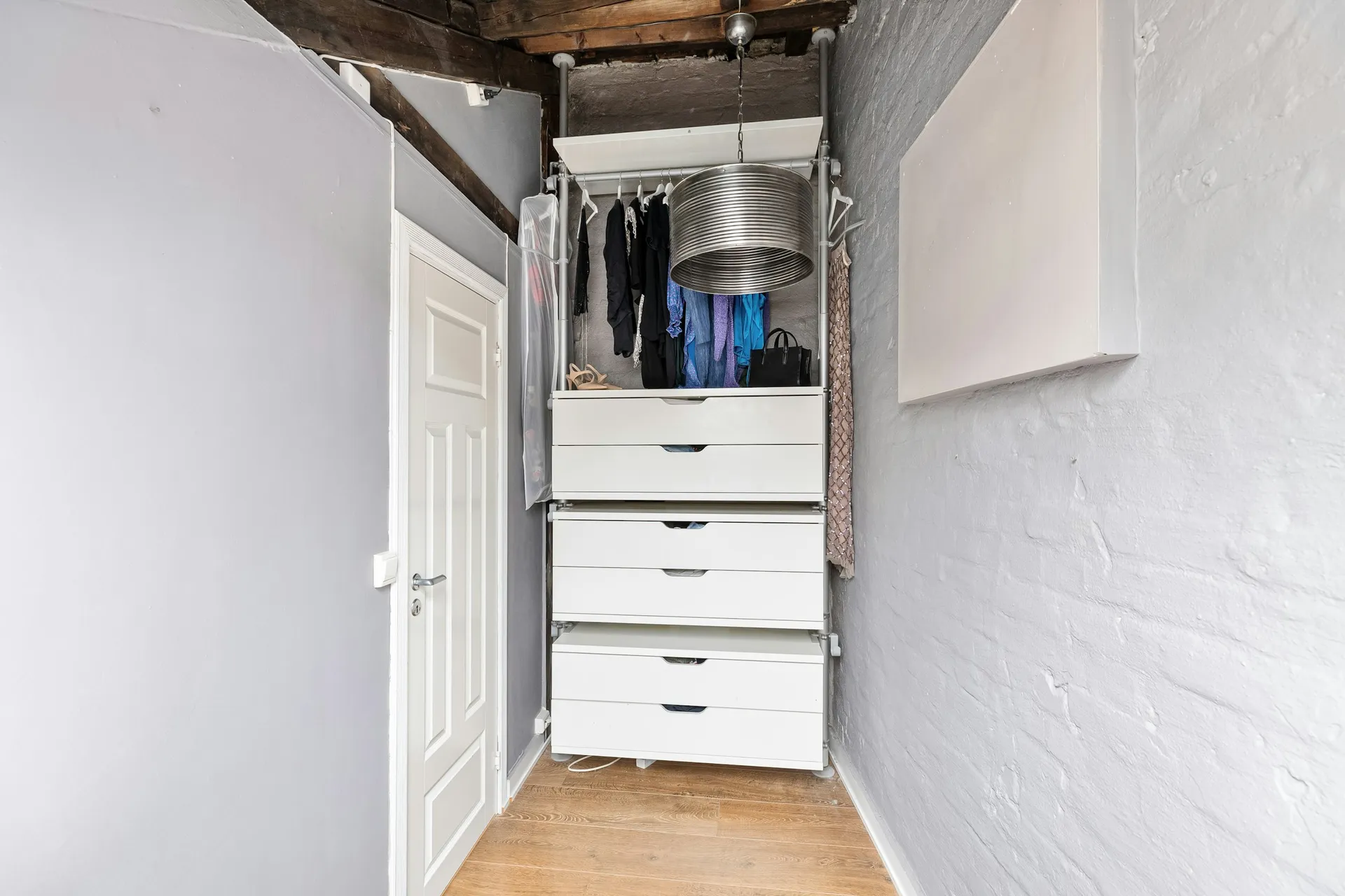 Narrow storeroom with a white drawer tower and open shelving at the end
