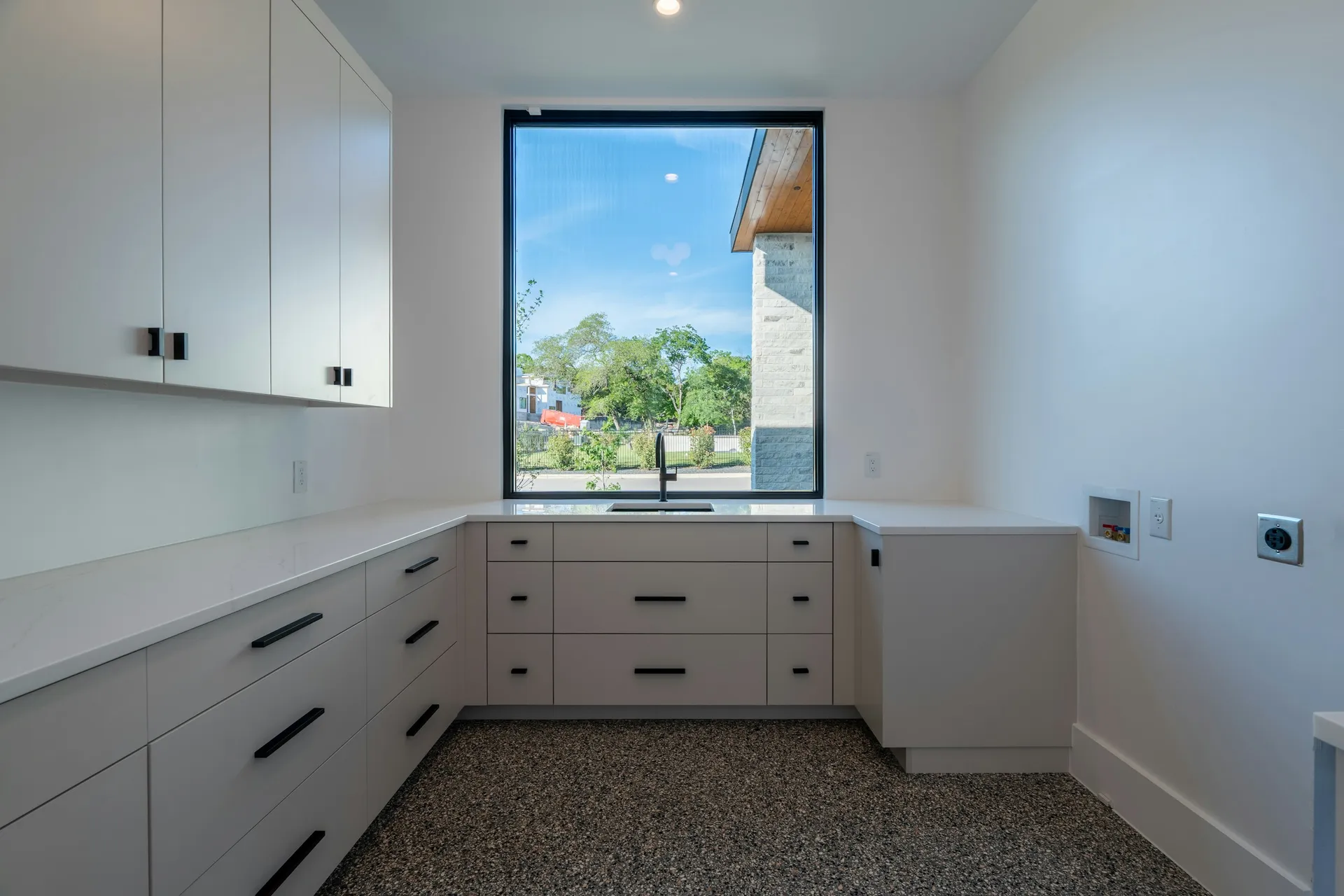 White utility room lined with base and wall cabinets under a large window