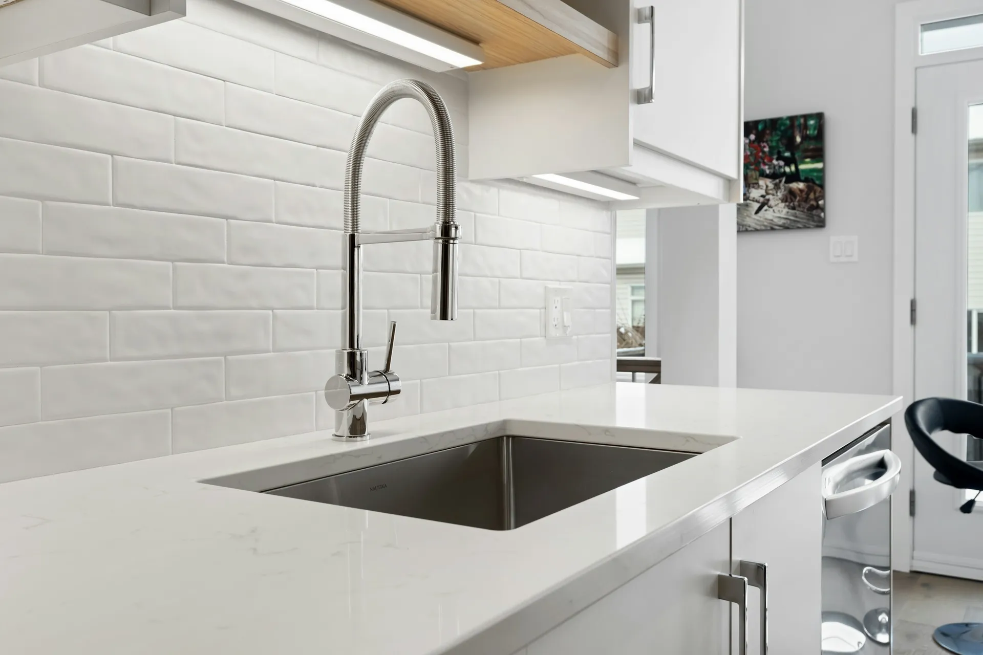 Stainless steel undermount sink with a matt black pull-out tap in a stone countertop